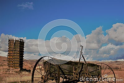 Antique farm equipment and water tower in front of snow capped mountains Stock Photo