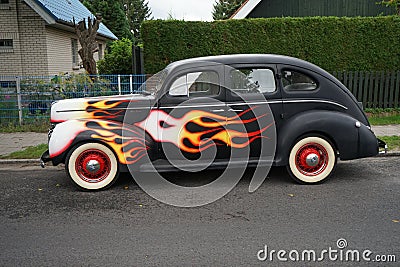 An antique Ford De Luxe Sedan car painted in fiery colors. Ford Motor Company introduced its De Luxe Ford line in 1938. Berlin Stock Photo