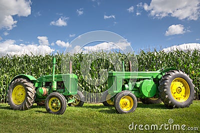 Antique Vintage Green John Deere Tractors in front of a corn field with a blue sky. Editorial Stock Photo