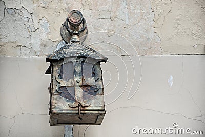 Antique metal forged wall lamp on a light cracked wall Stock Photo