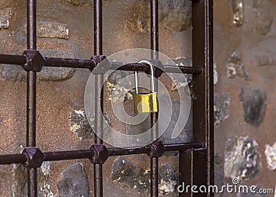 Padlock on the lattice. Antique metal grill on which a golden castle weighs against a stone wall Stock Photo