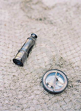 Antique nautical telescope and old metal compass on texture mesh net surface Stock Photo