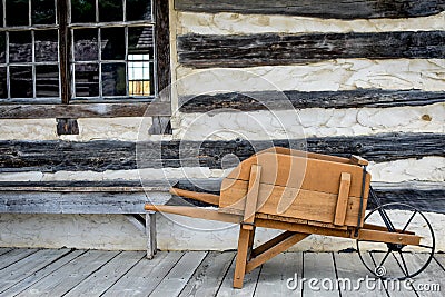 Antique Wooden Wheelbarrow, Log Cabin Stock Photo