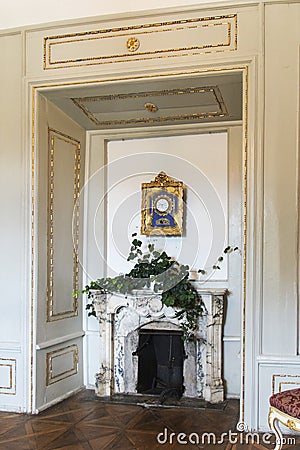 Antique pendulum clock in gilded rosette frame over the marble fireplace Editorial Stock Photo