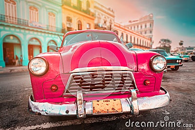 Antique pink car inext to colorful buildings in Old Havana Stock Photo