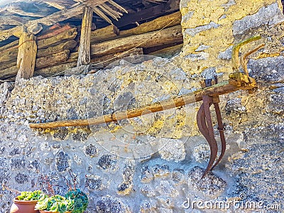 antique plow hung on stone wall of country house Stock Photo