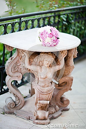 Antique statue supporting a table with wedding bouquet Stock Photo