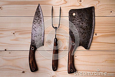 Antique stylized butcher`s set. Cleaver, knife and fork on a wooden background. View from above Stock Photo