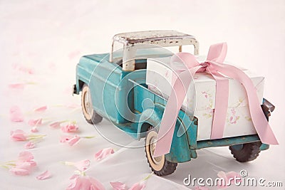 Antique toy truck carrying a gift box with pink ribbon Stock Photo