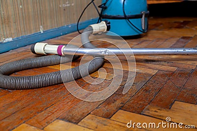 Blue vacuum cleaner stands on old parquet floor Stock Photo