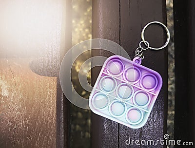 Antistress toy keychain hanging on a blue bag, on a park bench. Silicone Stress Relief Toy Stock Photo