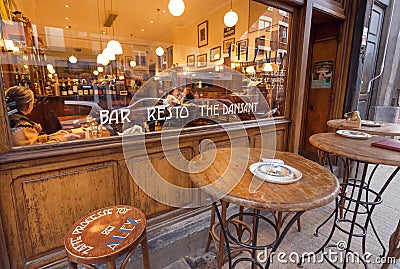 Retro restaurant window with drinkers and eating people and tables for smoking outside Editorial Stock Photo