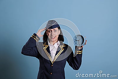 Anxious flight attendant holding retro alarm clock, running late Stock Photo