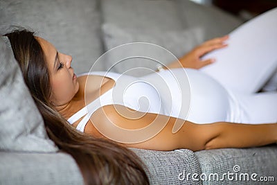 Anxious pregnant woman lying on the sofa with pain Stock Photo