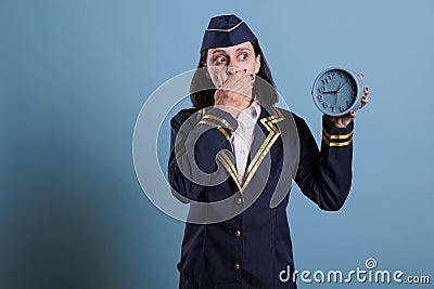 Anxious stewardess holding retro alarm clock Stock Photo