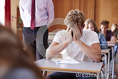 Anxious Teenage Student Sitting Examination In School Hall Stock Photo