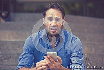 Anxious upset scared man looking at phone seeing bad news Stock Photo