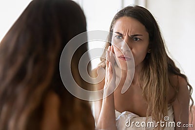 Anxious young woman look in mirror worry about skin problems Stock Photo