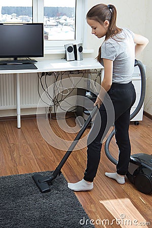 Apartment cleaning.A young European girl with long hair vacuuming a room Stock Photo