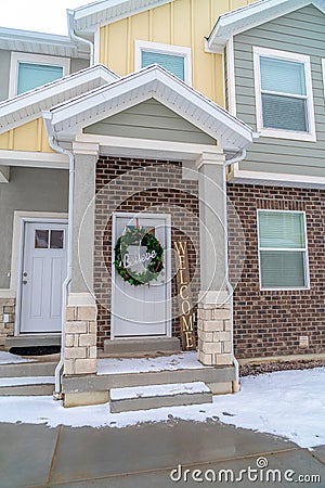 Apartment entrance with snowy steps leading to front door with holiday wreath Stock Photo