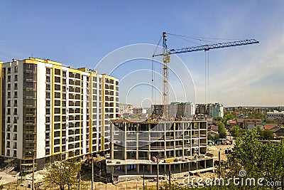 Apartment or office tall building under construction. Working builders and tower cranes on bright blue sky copy space background Stock Photo