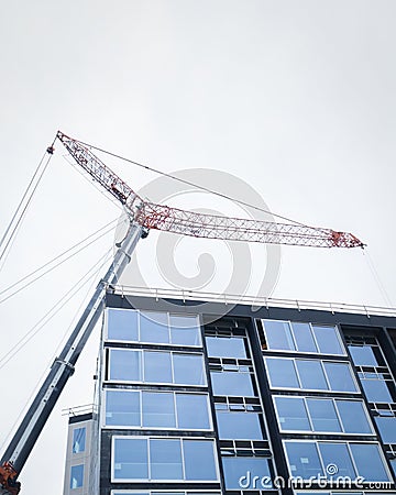 Apartment under construction. Construction crane above the building against a cloudy sky. Auckland. Vertical format Stock Photo
