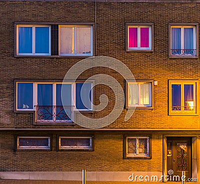 Apartments complex lighted by night, Belgian homes, building exterior with windows and front door Stock Photo