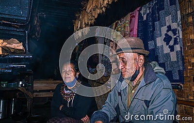 Apatani tribal couple at their home near fire place cooking food at evening from flat angle Stock Photo