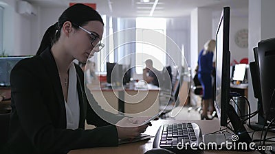 Apathie, Geschäftsmädchen mit Gläsern arbeitet im Büro am Computer und benutzt Handy stock video footage Apathie, Geschäftsmädchen mit Gläsern arbeitet im Büro am Computer und benutzt Handy stock video footage