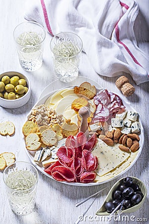 Aperitif, champagne and snack of sausage, cheese, nuts, olives and crackers on a light background. Stock Photo