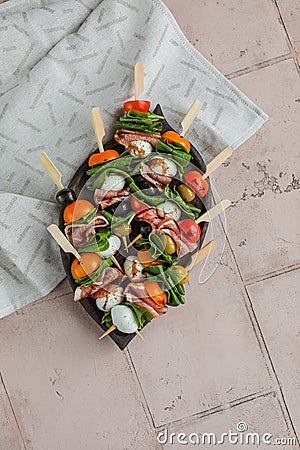 Apetizers on wooden skewers. Snacks from mozzarella, cherry tomatoes, salmon, spinach and olives. Stock Photo