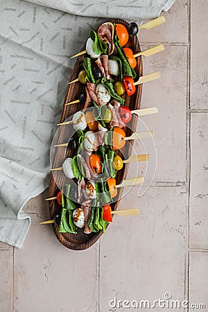 Apetizers on wooden skewers. Snacks from mozzarella, cherry tomatoes, salmon, spinach and olives. Stock Photo