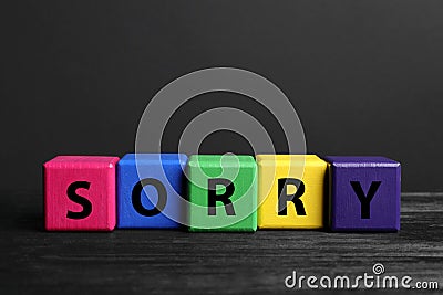 Apology. Word Sorry made of colorful cubes on black wooden table Stock Photo