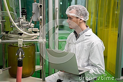 Apothecary scientist recording data from CBD oil extractor in laboratory. Editorial Stock Photo