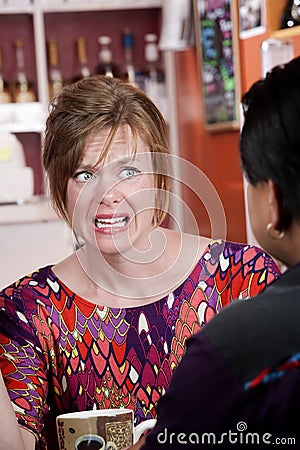 Appalled woman in coffee house with male friend Stock Photo