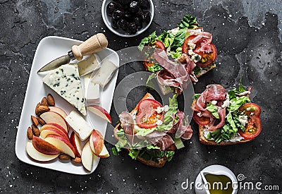 Appetizer, aperitif, snack table - gorgonzola, brie cheese, dried olives, apple, almonds and prosciutto, tomatoes, green salad Stock Photo