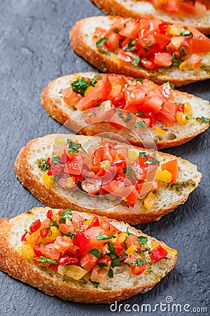 Appetizer bruschetta with chopped vegetables on ciabatta bread on stone slate background close up. Stock Photo