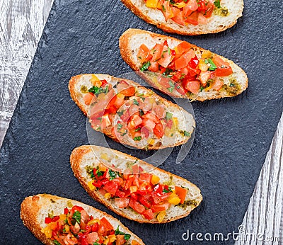 Appetizer bruschetta with chopped vegetables on ciabatta bread on stone slate background close up. Stock Photo