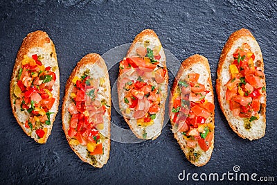 Appetizer bruschetta with chopped vegetables on ciabatta bread on stone slate background close up. Stock Photo