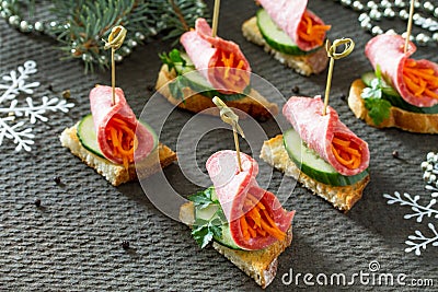 Appetizer canape on crispy bread with cucumber, carrots and sausage. Beautiful Christmas and New Year`s food background. Stock Photo