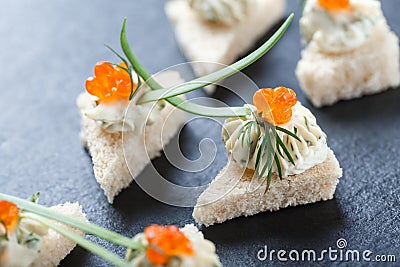 Appetizer canape with red caviar and cream cheese on stone slate background close up. Stock Photo