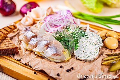 Appetizer. Herring, boiled potato, toasted bread, pickles, onion on wooden board Stock Photo