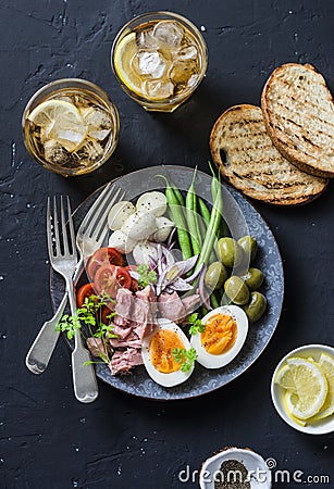 Appetizer table - plate of canned tuna, green beans, mozzarella cheese, tomatoes, boiled egg, olives, grilled bread and two glasse Stock Photo