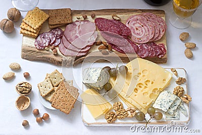 Appetizer of various types of sausages, meats, cheeses and crackers on a wooden board, served to wine Stock Photo