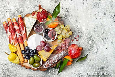 Appetizers table with antipasti snacks. Cheese and meat variety board over grey concrete background. Top view, flat lay. Stock Photo