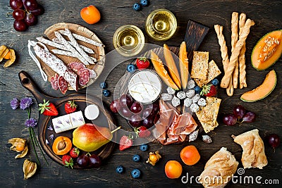 Appetizers table with italian antipasti snacks and wine in glasses. Cheese and charcuterie variety board over rustic wooden table Stock Photo