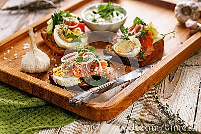 Appetizing canapes or sandwiches with smoked salmon. Toast with fish, soft cheese, eggs, onion rings and salad Stock Photo