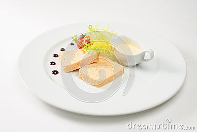 High kitchen, casserole on a white plate with greens and a sauce bowl Stock Photo