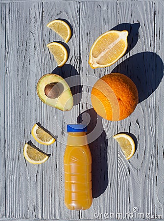 Appetizing composition of a bottle of orange juice, a whole orange, slices and half of a lemon, avocado halves with a stone Stock Photo