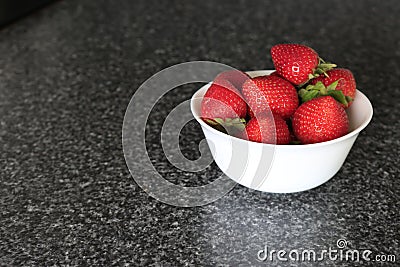 Appetizing fresh strawberry in a white bowl on a gray background. Stock Photo